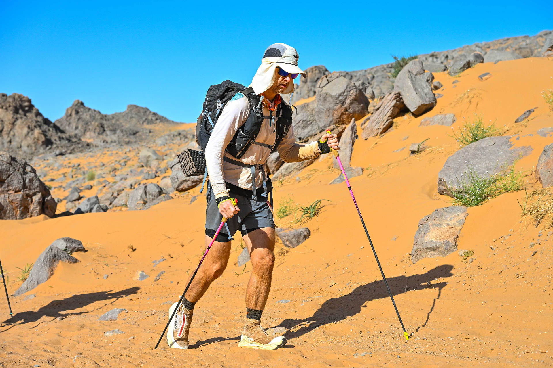 Derrick Tate climbing a sand dune with poles during the Marathon des Sables